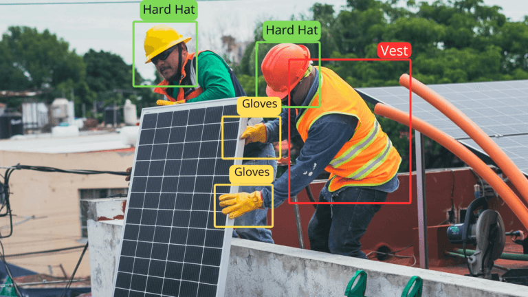Two workers wearing hard hats, gloves, and vests install a solar panel on a rooftop. Workplace Safety