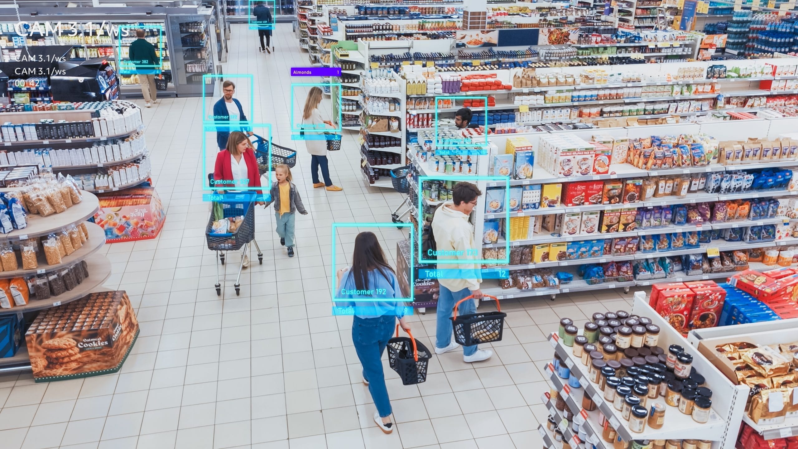 Supermercado visto de cima, mostrando vários clientes caminhando entre corredores de produtos. Alguns empurram carrinhos e outros carregam cestas de compras. Caixas e prateleiras estão cheias de alimentos e itens variados. Ao redor das pessoas, há molduras digitais destacando cada cliente, simulando uma tecnologia de monitoramento por inteligência artificial. Supermarket viewed from above, showing multiple customers walking through aisles filled with products. Some people are pushing shopping carts while others carry shopping baskets. Shelves and displays are stocked with various food items. Around each person, digital frames highlight the customers, simulating artificial intelligence monitoring technology.