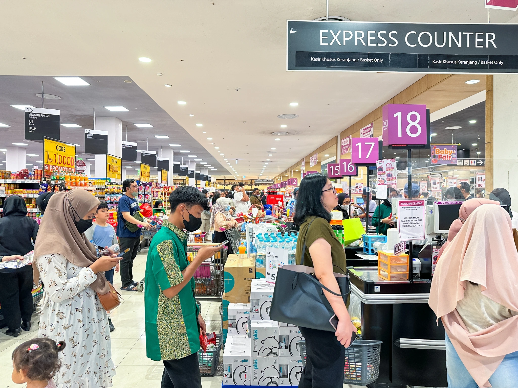 Área de checkout de supermercado movimentada com vários clientes aguardando em filas longas nos caixas numerados, ilustrando congestionamento e o risco de abandono de filas em ambiente varejista. Busy supermarket checkout area with multiple customers waiting in long lines at numbered checkout counters, illustrating the risk of queue abandonment in a retail environment.